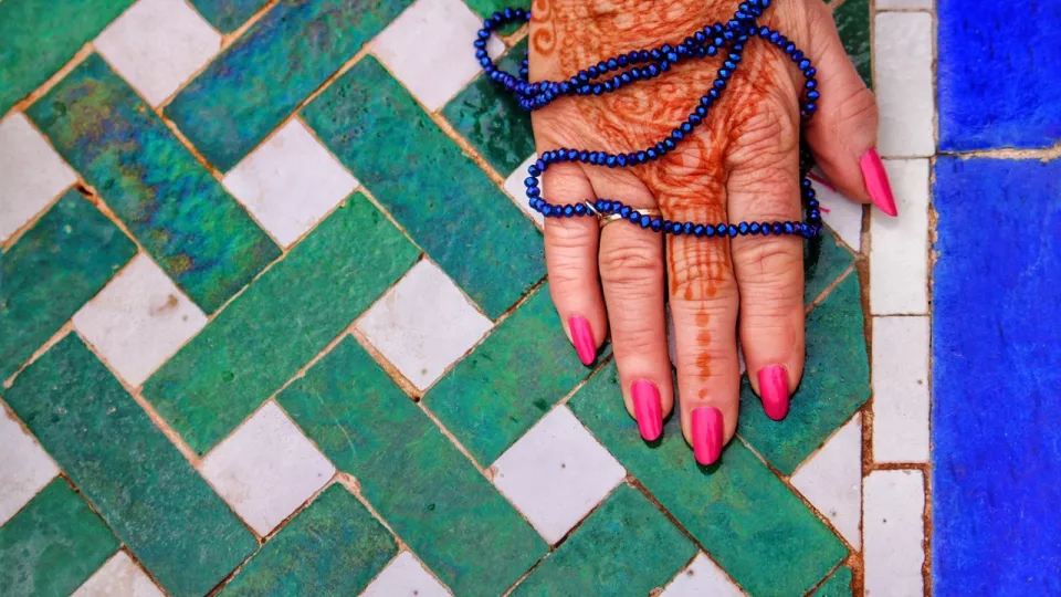 Hands painted with henna holding a mala, Photo: Pixabay